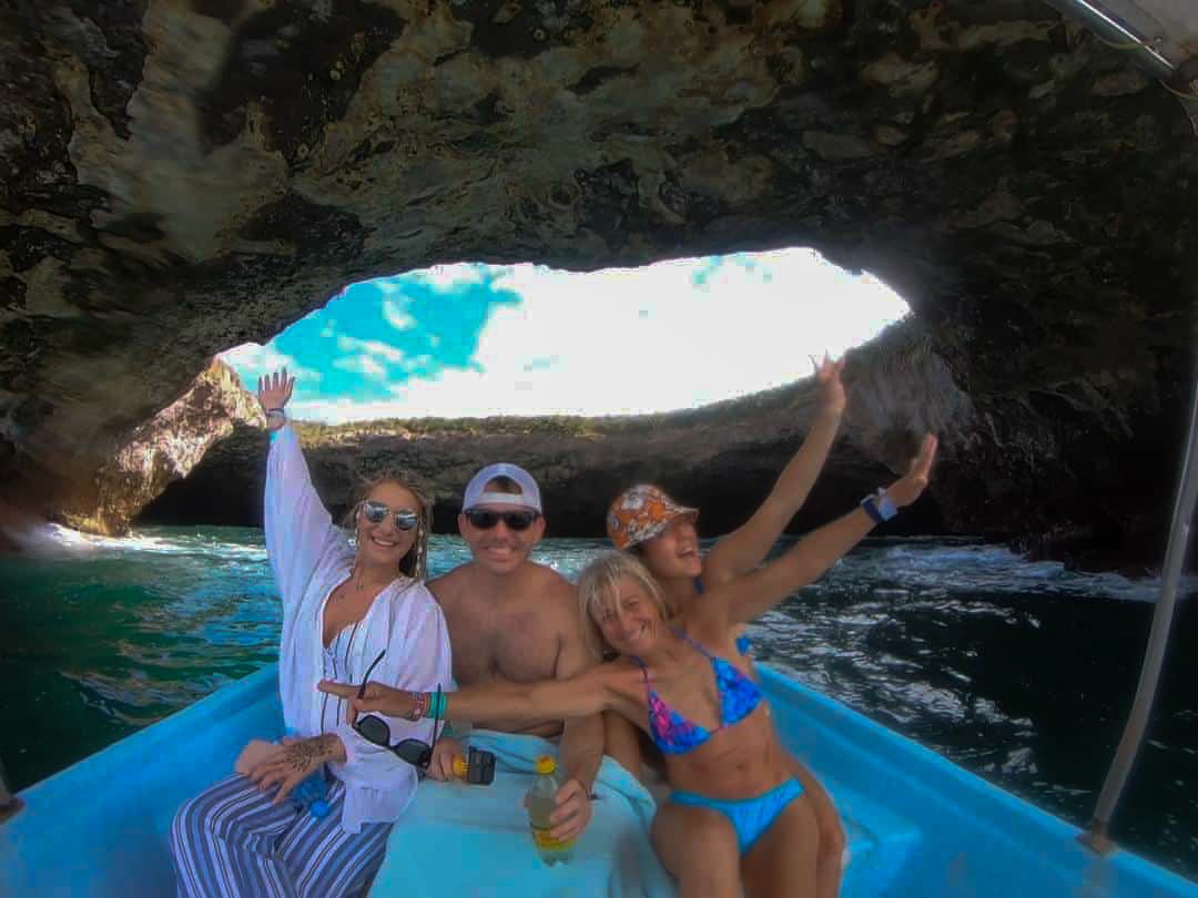 Grupo de viajeros a bordo de nuestra lancha bajo un arco de roca volcánica en las Islas Marietas