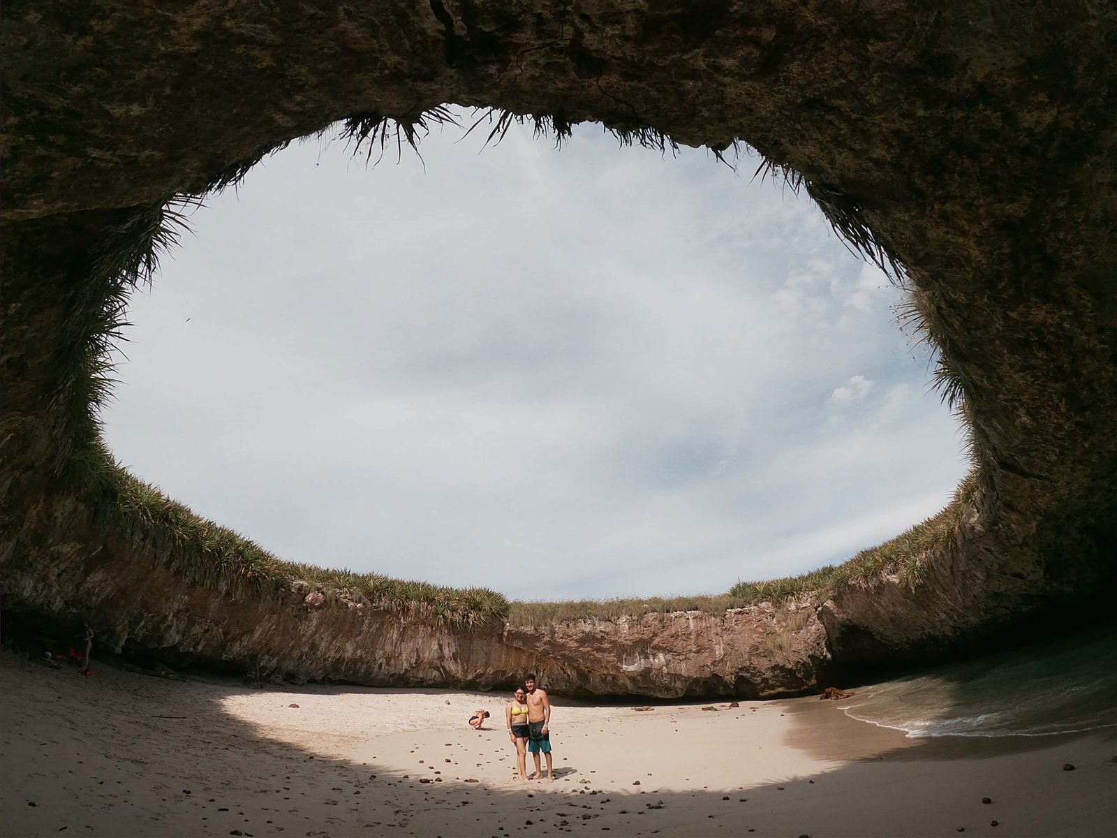Pareja en la Playa del Amor con el cielo enmarcado por el cráter abierto de la isla